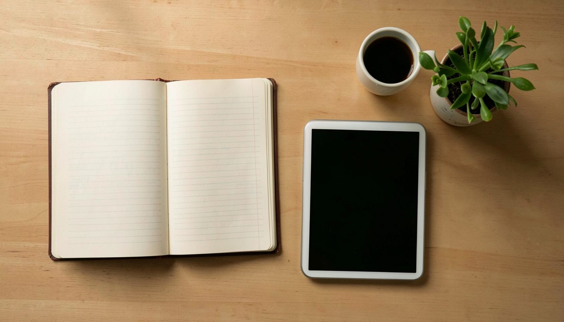 A warm overhead flat-lay of educational objects on a wooden desk: an open notebook, a tablet, a coffee cup, and a small potted plant, bathed in soft natural light with gentle shadows.